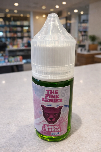 Bottle of 'The Pink Series' candy frozen sour e-liquid on a counter.
