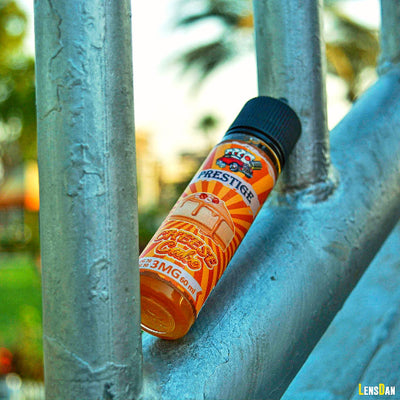 Orange vape device with a label on a metal surface outdoors