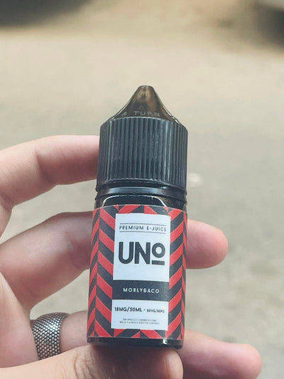Hand holding a bottle of UNO e-juice with a blurred background