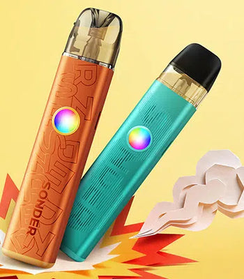 Two portable vape devices shown on a yellow graphic background: one metallic copper-orange device with embossed lettering and a rainbow button, and one metallic teal device with a black mouthpiece and a rainbow button. Paper-style flame and cloud props appear at the bottom.