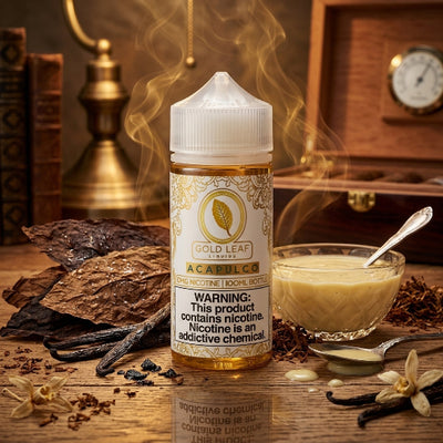 A bottle of Gold Leaf Liquor Acapulco single nicotine 100ml e-liquid stands on a wooden table with a glass bowl of creamy yellow liquid, spices, vanilla beans, and steam rising. The background shows a warm, vintage wooden chest and brass lantern.