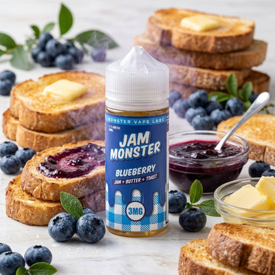 A bottle of Jam Monster Blueberry e-liquid by Monster Vape Labs stands on a light marble surface surrounded by blueberries, toast with butter and jam, and small bowls of jam and butter. The bottle label is blue and white with the brand name 'JAM MONSTER' prominently visible.